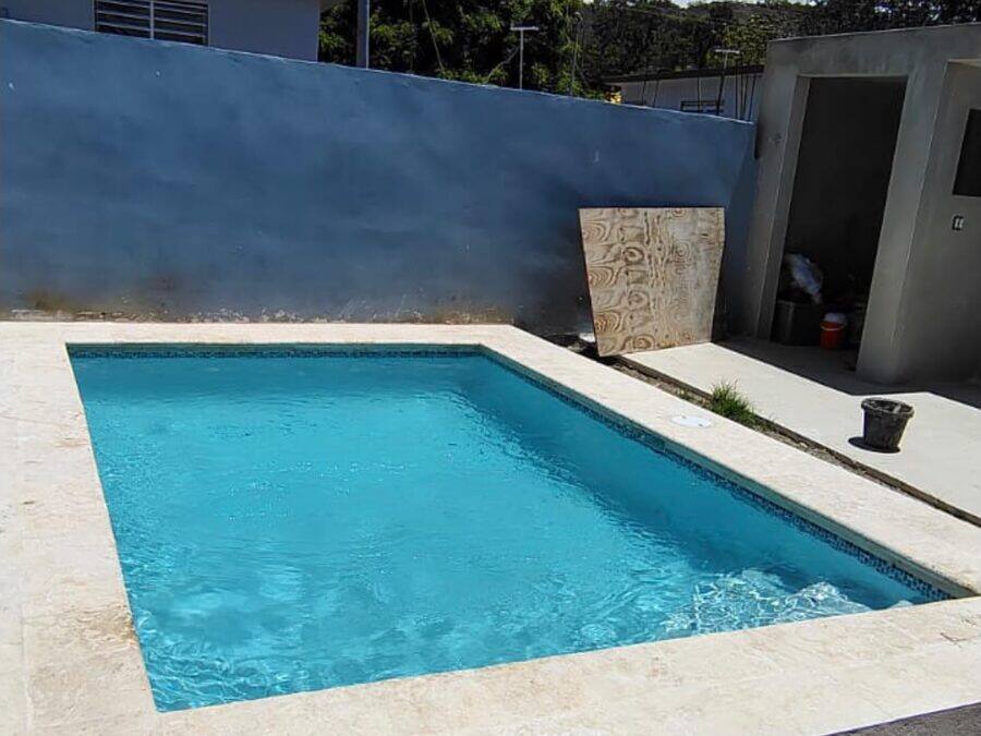 Piscina rectangular en concreto con muro perimetral y aceras de travertino